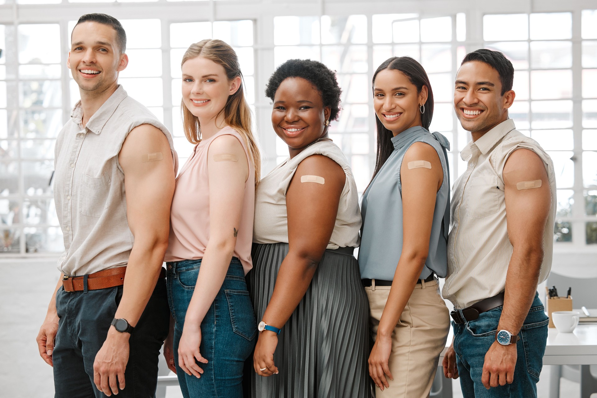 Covid vaccine, safety and health colleagues with plaster after vaccination for business office protocol or policy and protection against the virus. Smiling workers standing together, showing support
